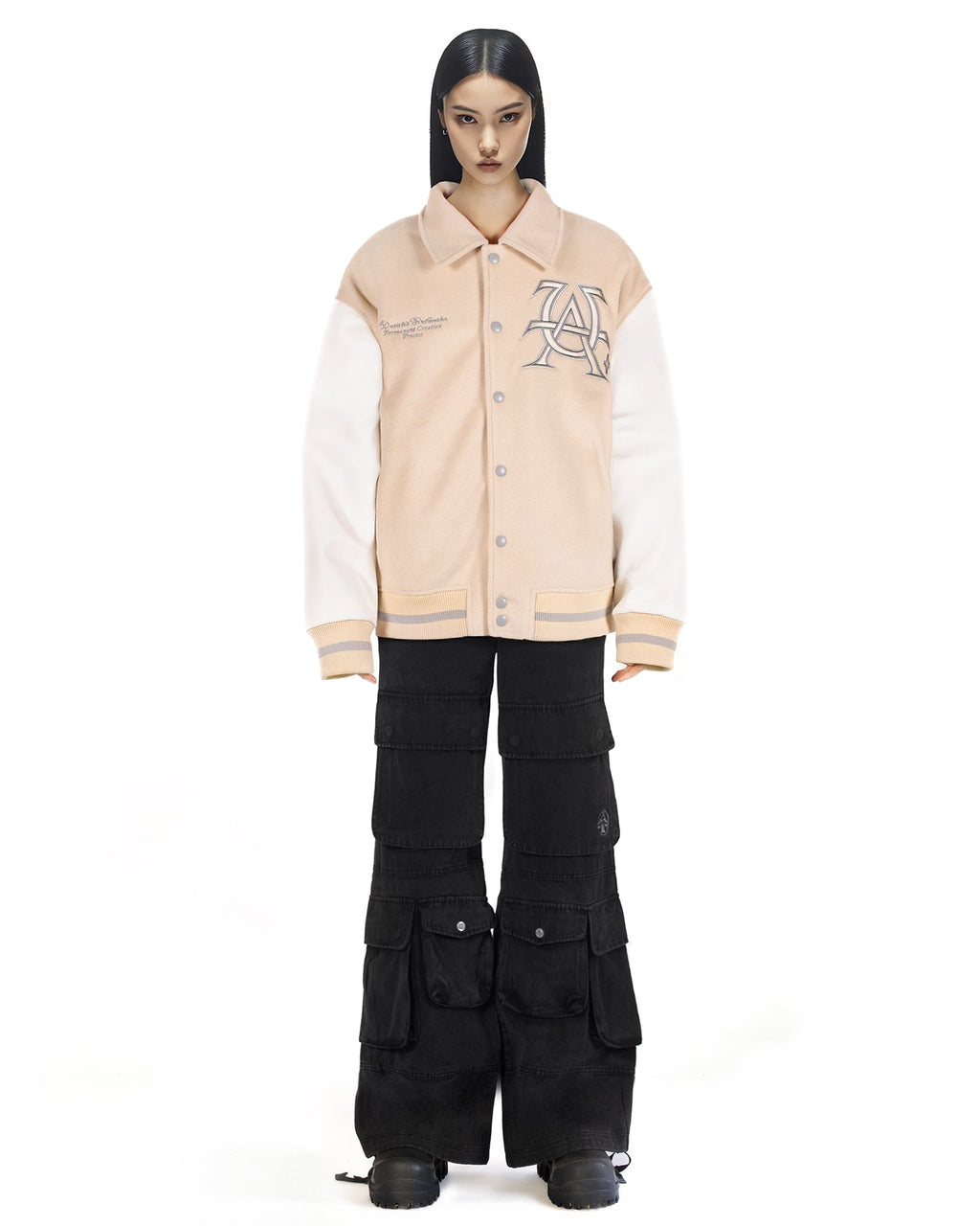 Untitled Artworks “Hunting Oat” varsity jacket in tan (oat) with embroidered hunting graphics and oversized letterman fit. on model front 
