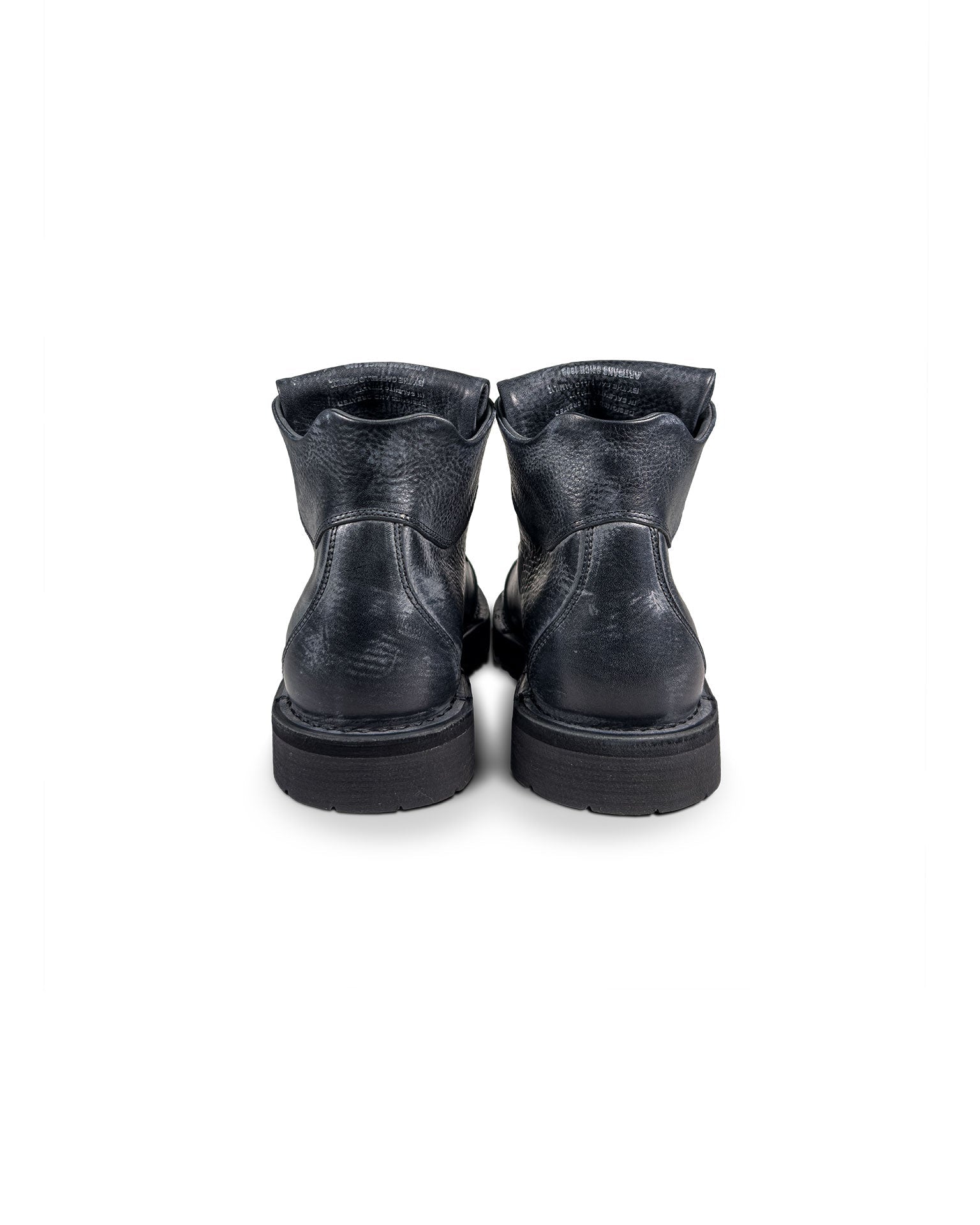 Close-up back view of the Untitled Artworks x Fracap Destroyer Boot in black, showcasing its spray-effect finish, oversized fold-over tongue, and antique brass eyelets.